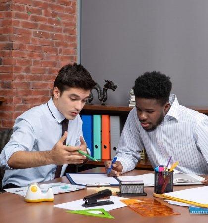 front-view-two-busy-businessmen-sitting-desk-discussing-project-office_140725-109539 (1)
